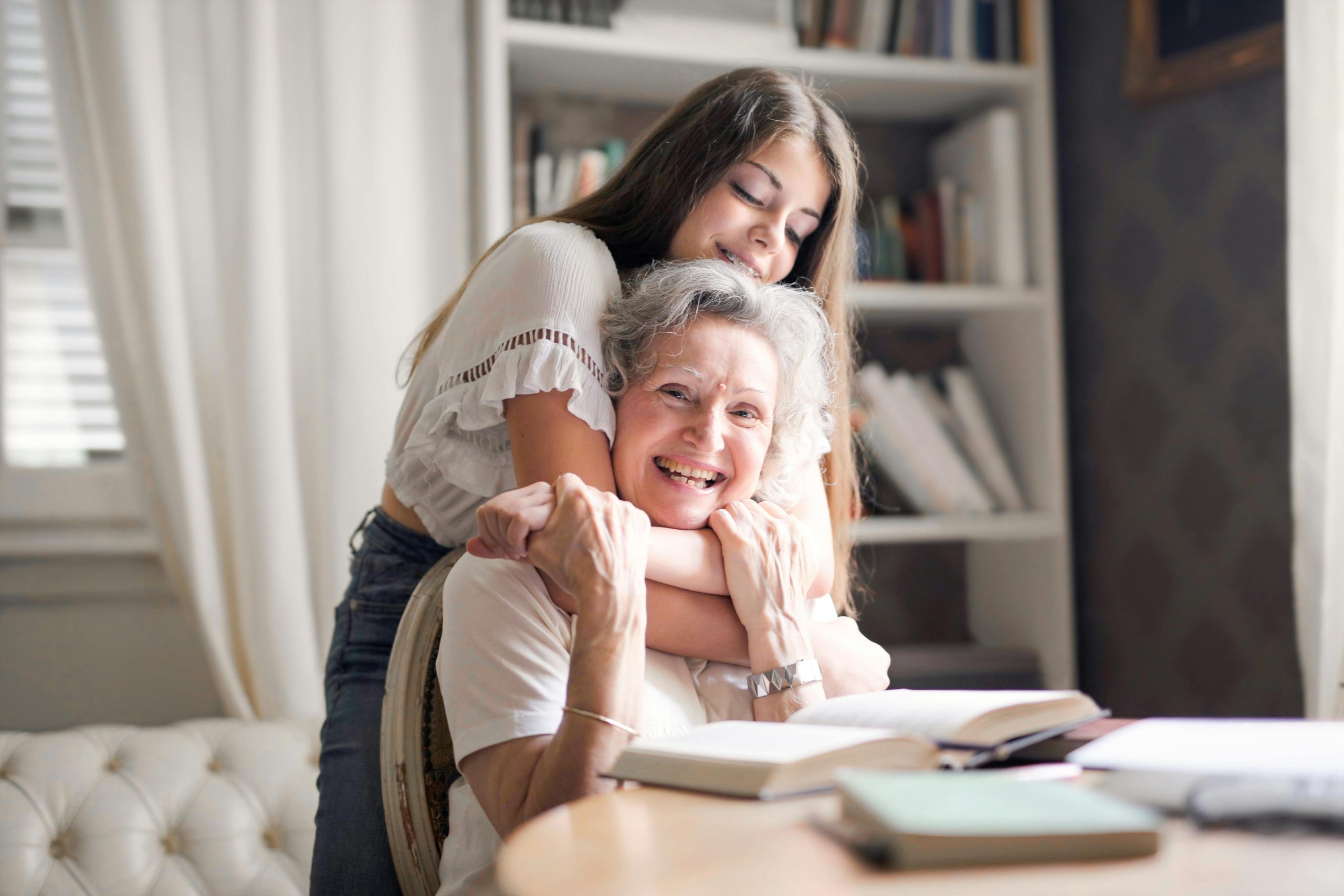 A joyful moment of a granddaughter hugging her grandma at home, showcasing love and family bond.